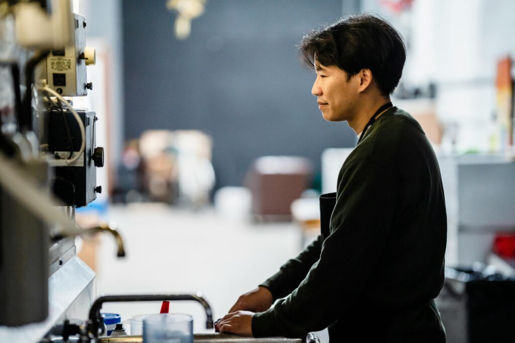 Asian man focused on work in a modern industrial workspace. Ideal for business and technology themes.